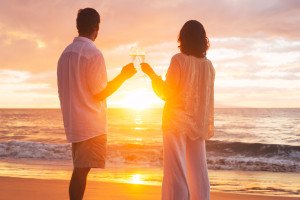 Happy Romantic Couple Enjoying Glass of Champagne at Sunset on the Beach. Vacation Travel Retirement Anniversary Celebration.