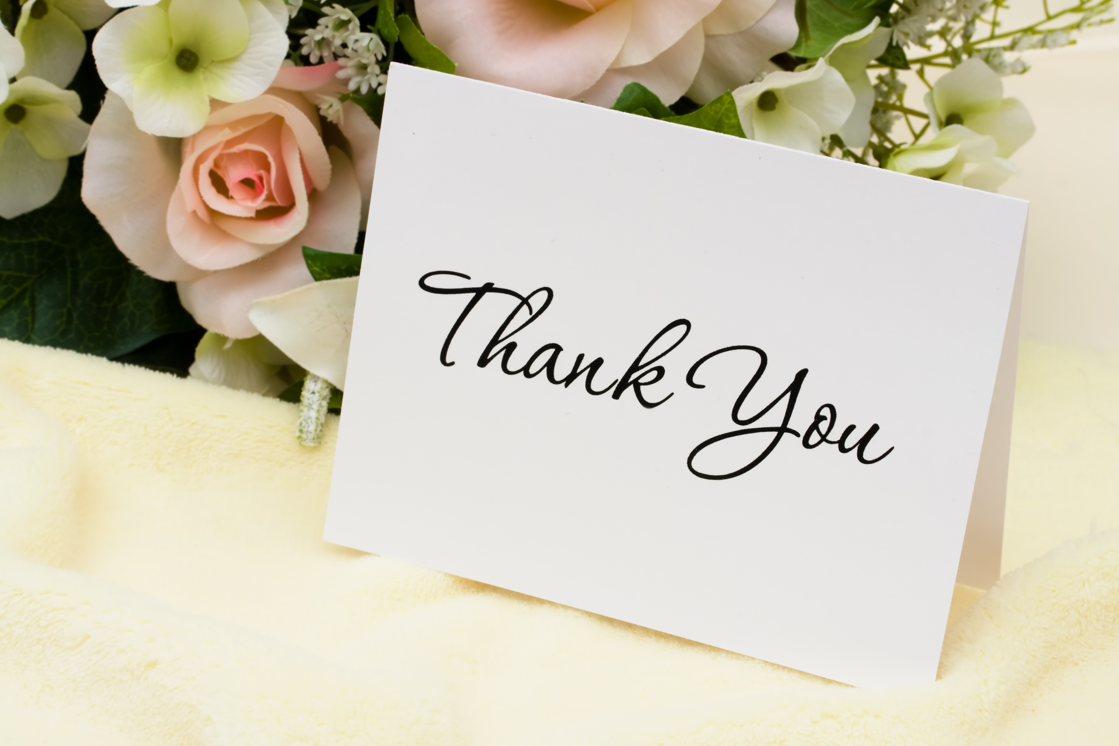 A bouquet of flowers with a thank you card thank you card